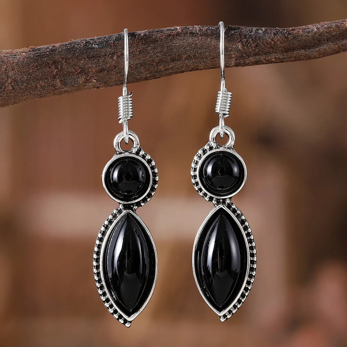 A pair of vintage geometric drop earrings with black and purple stones in a bohemian style.