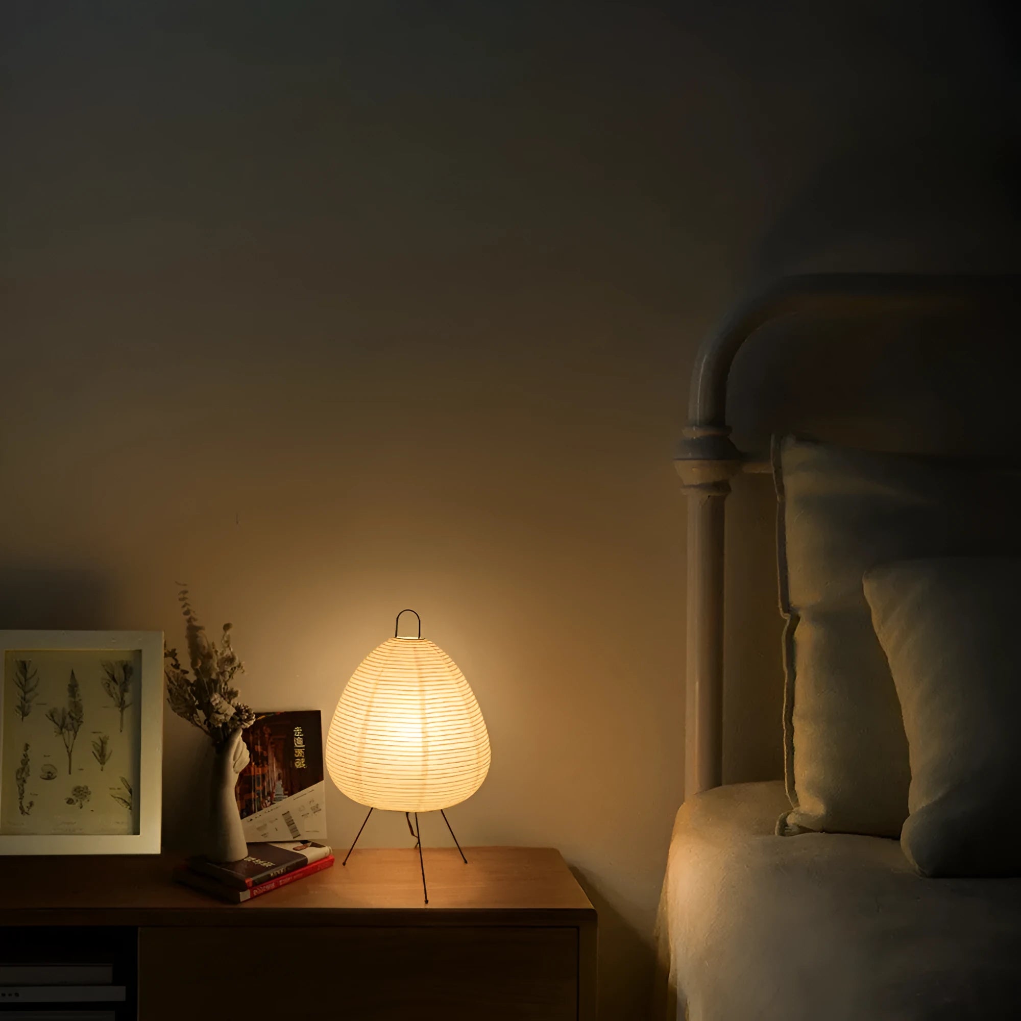 Japanese style table lamp with a white handmade paper lantern shade and aluminium base on a wooden table.