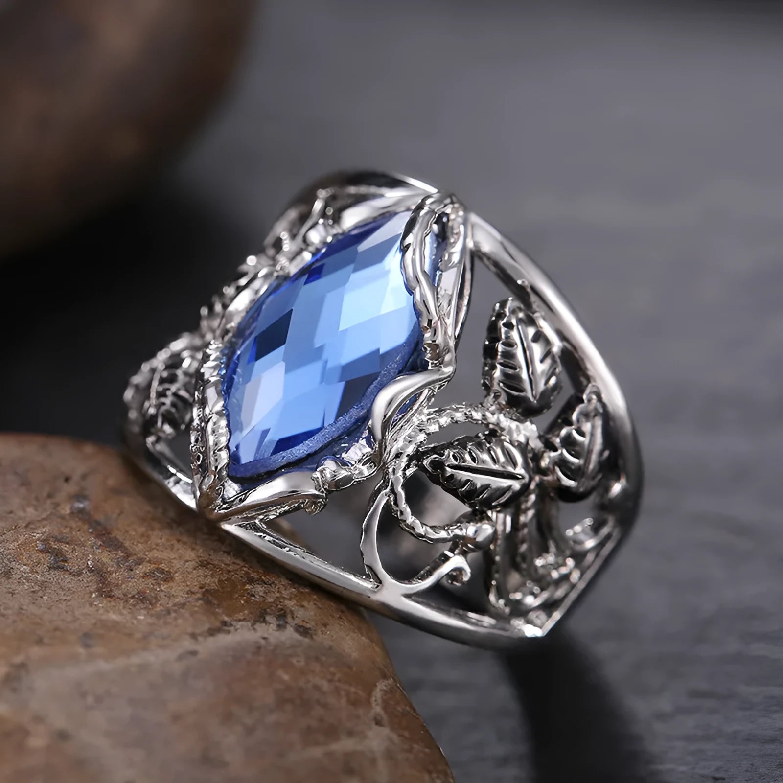 Women's horse eye shaped blue crystal alloy ring on a finger, showing geometric design.