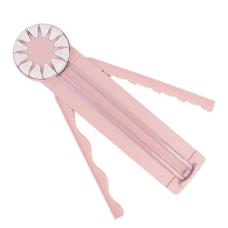 Pink plastic 12-in-1 paper cutting machine with dotted perforation wheel on craft table