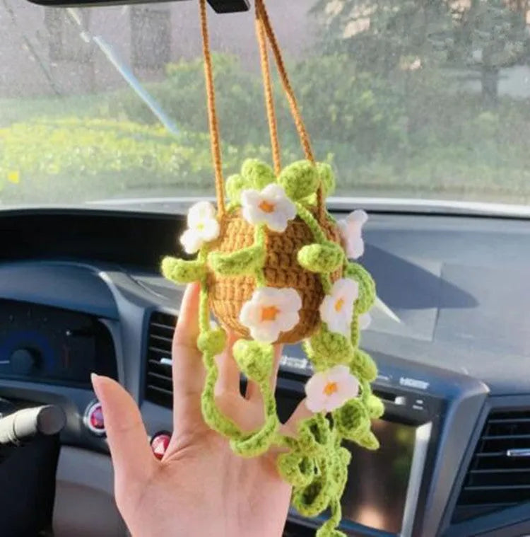Green and white knitted car plant decoration with hanging rope on car dashboard