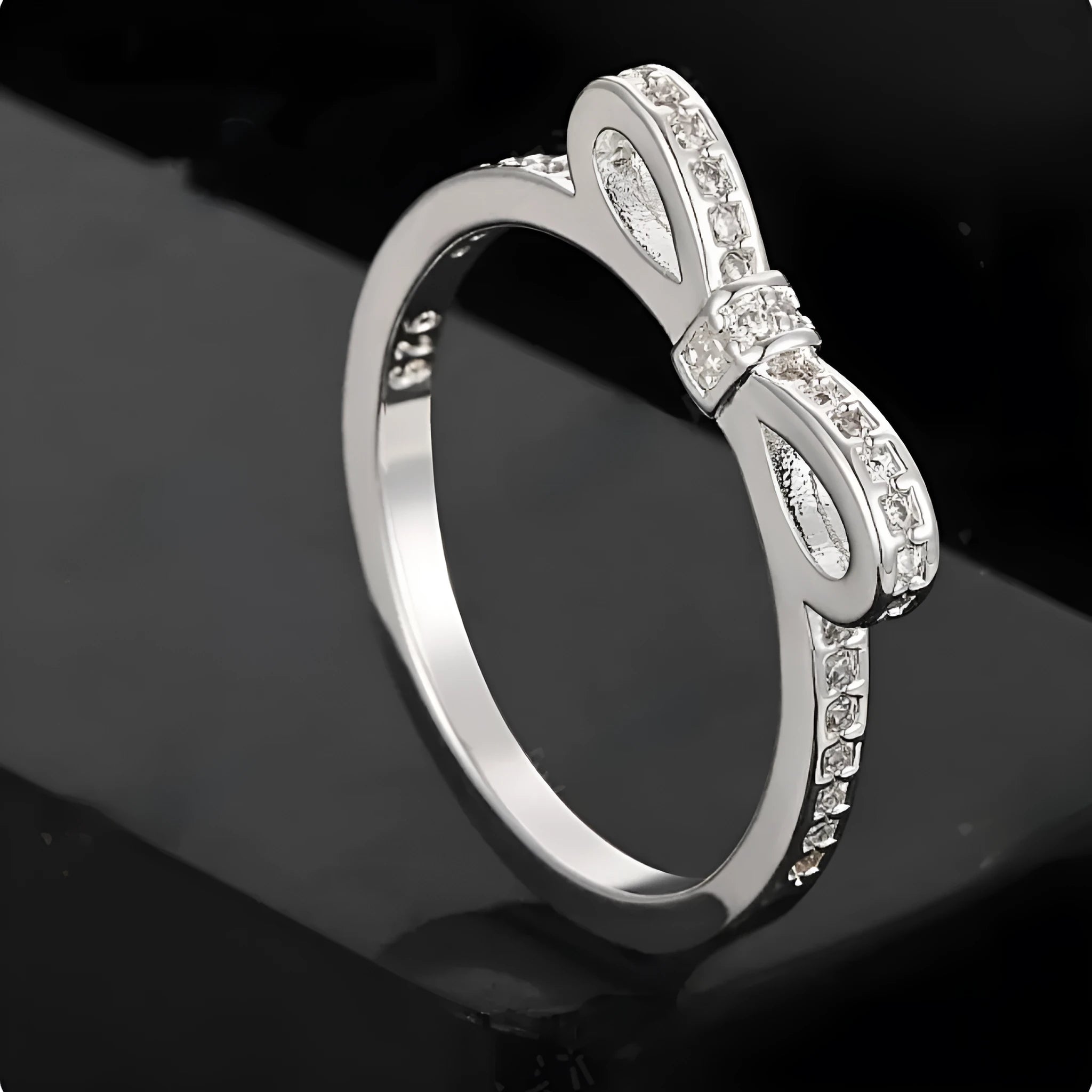 Silver bow ring with zircon crystal and rhinestone detailing on finger