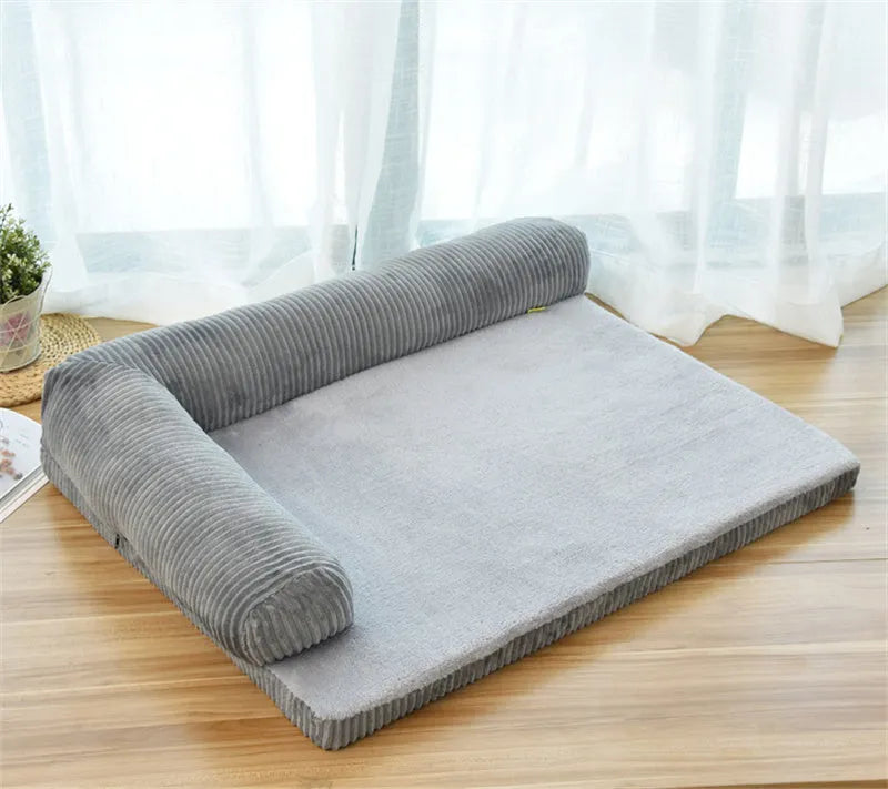 Corduroy dog sofa bed with bolster, shown in grey, placed on a wooden floor.