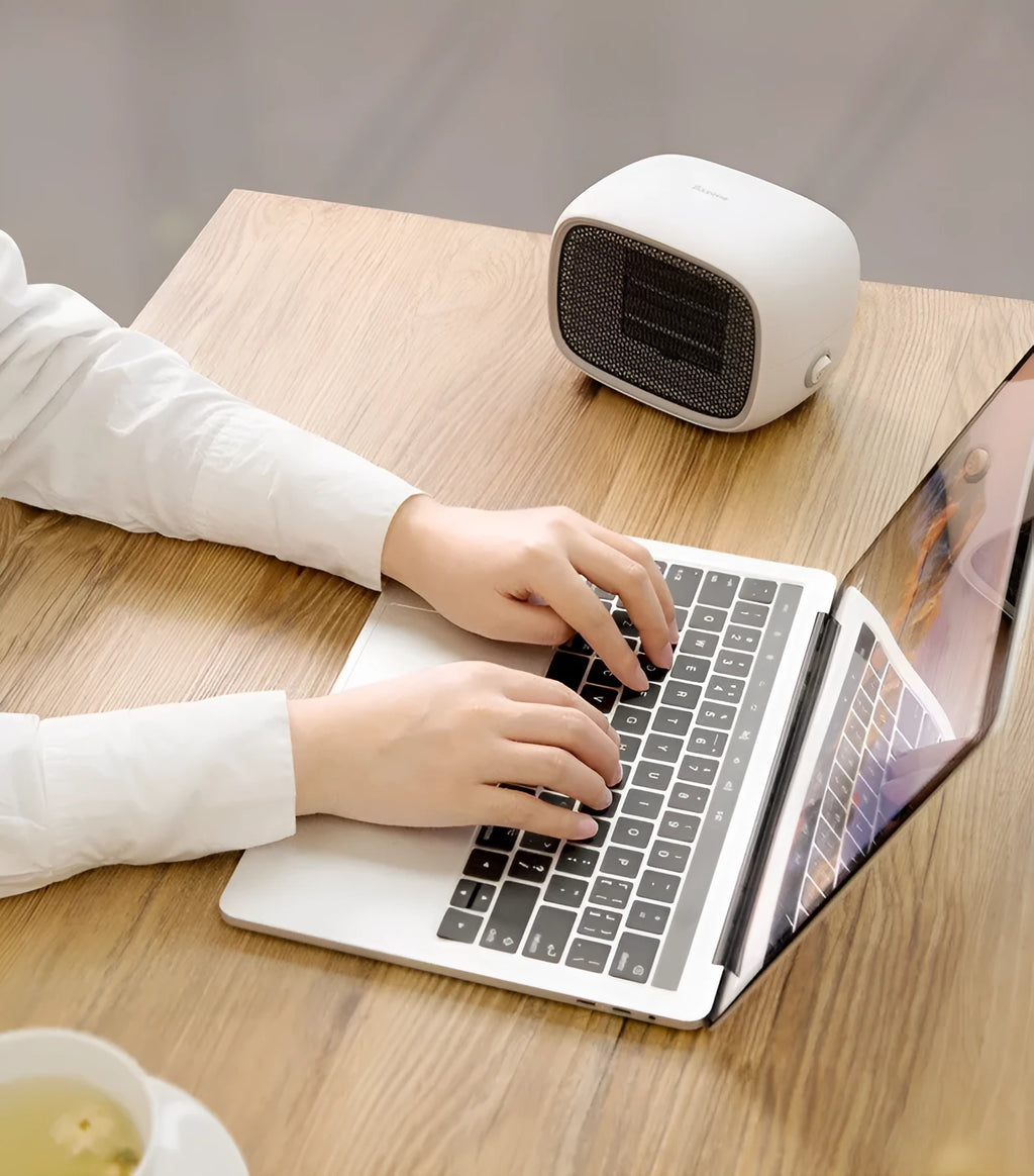Green mini PTC ceramic heater with metal mesh front on a wooden desk