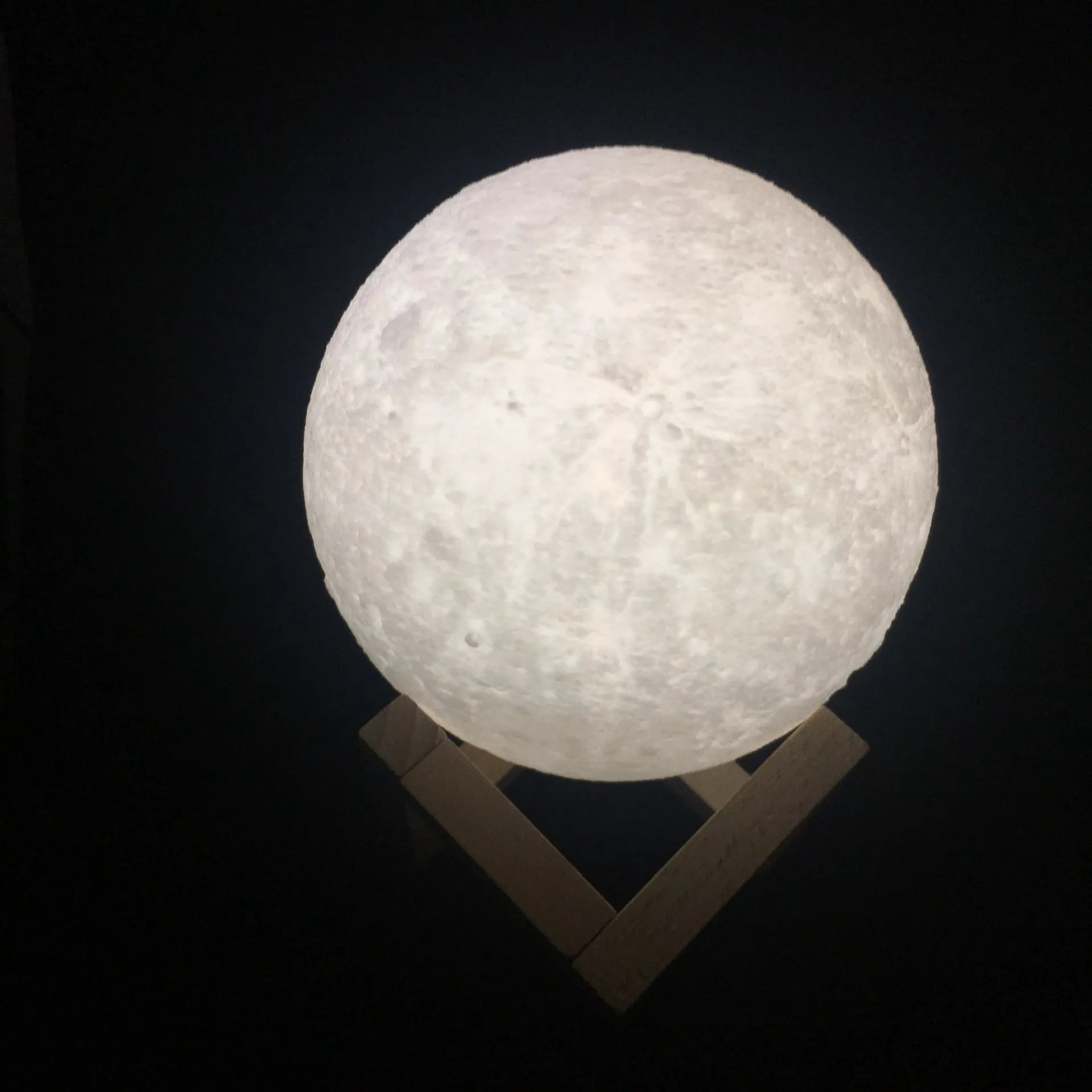 3D printed white moon lamp with textured surface on a wooden stand, showing touch ring at base.