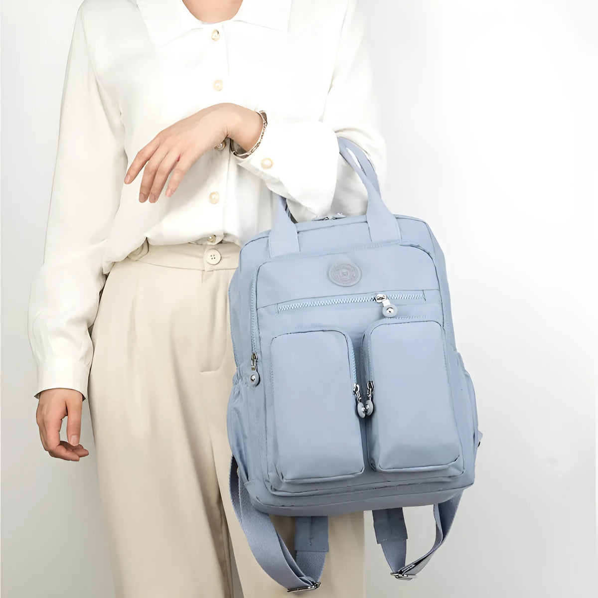 Waterproof women's travel backpack in grey showing front three-dimensional pocket and internal organiser compartments.