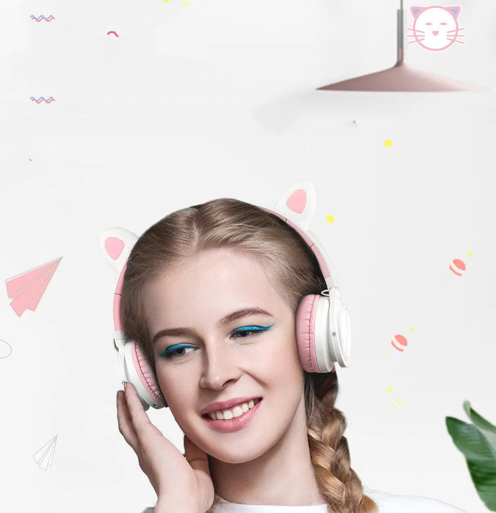 Pink and white wireless Bluetooth over-ear headset with a braided cable on a grey background.