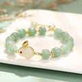 Women's rabbit charm bracelet with green aventurine stones and silver and gold plated metal links.