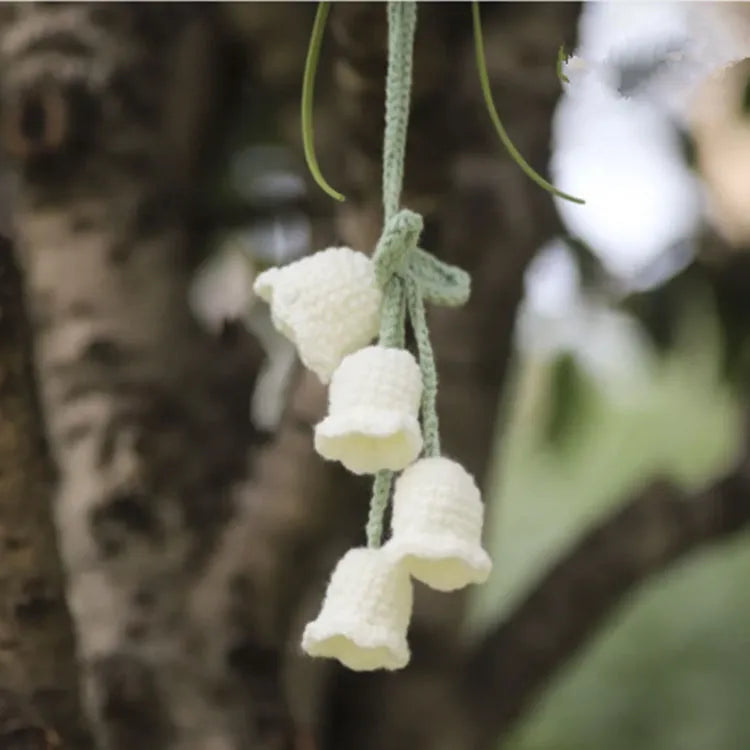 Green and white knitted car plant decoration with hanging rope on car dashboard