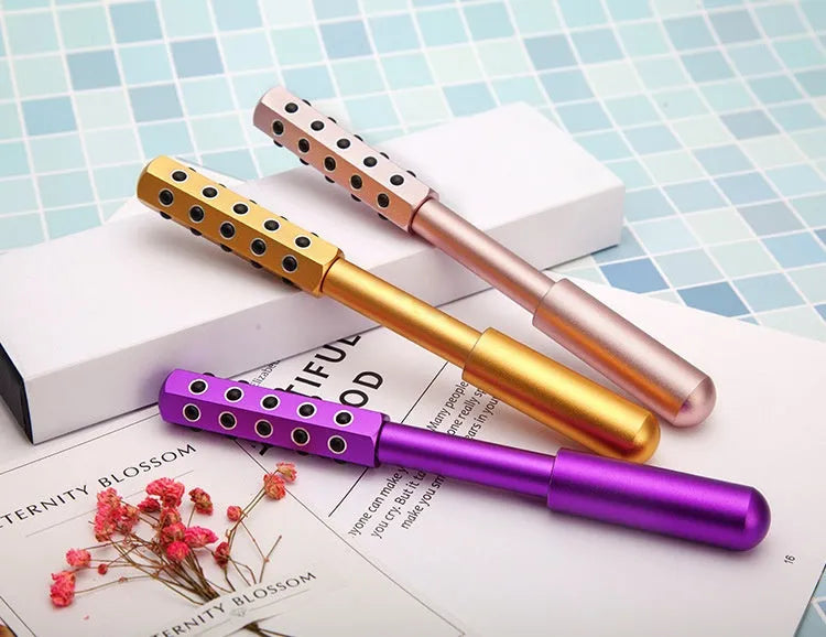 Purple handheld facial massage roller with textured surface on a white background.