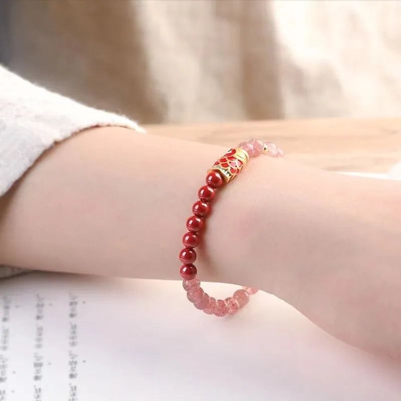 Purple cinnabar and strawberry quartz bracelet with koi and peach blossom design on a wrist.