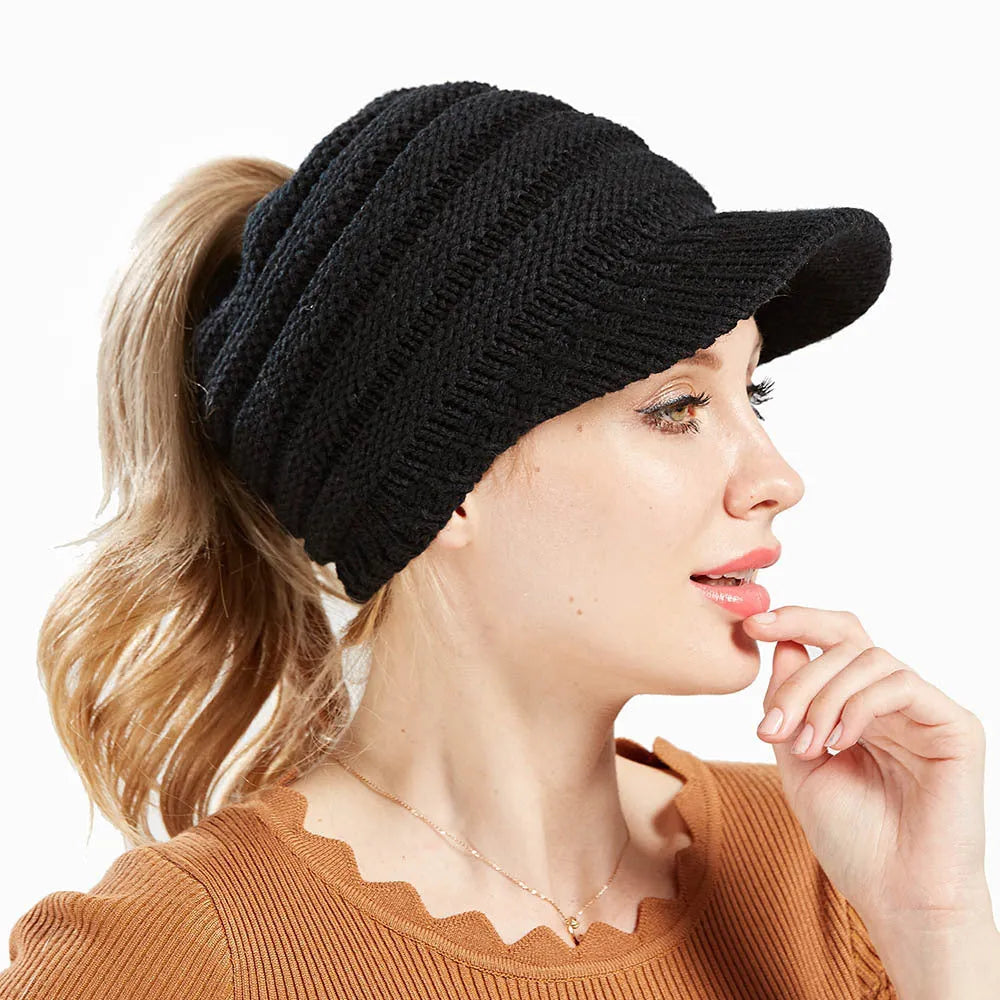 Woman wearing a soft knitted beanie with a ponytail pulled through the opening in the crown.
