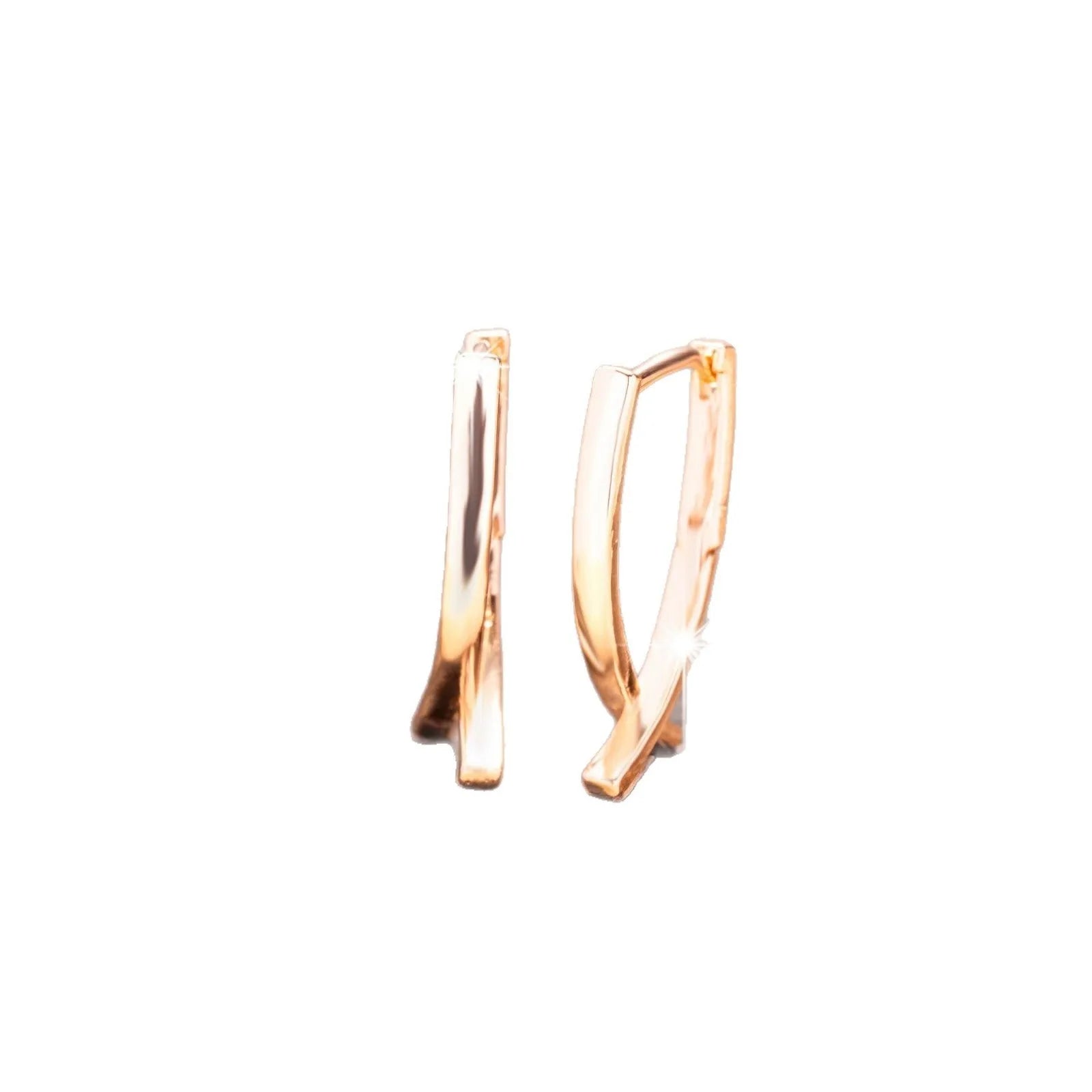 A pair of rose gold coloured cross shaped earrings made from copper on a white background.