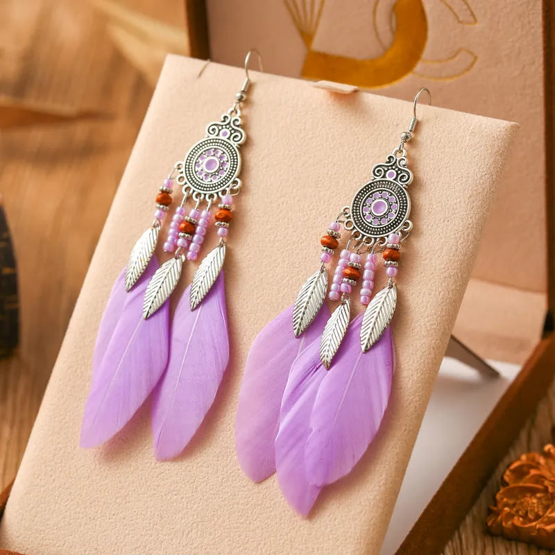 Close-up of a pair of bohemian-style feather-shaped earrings with a leaf pattern, in an alloy electroplated finish.