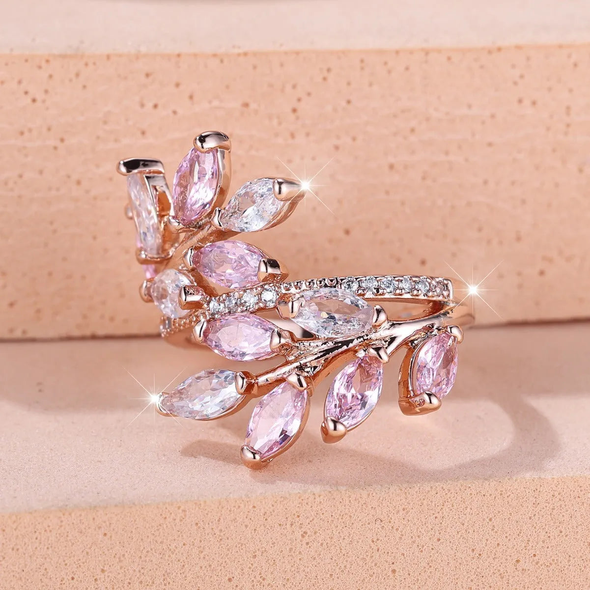 Adjustable opening copper leaf fashion ring with sparkling zirconia stones in a rose gold finish.