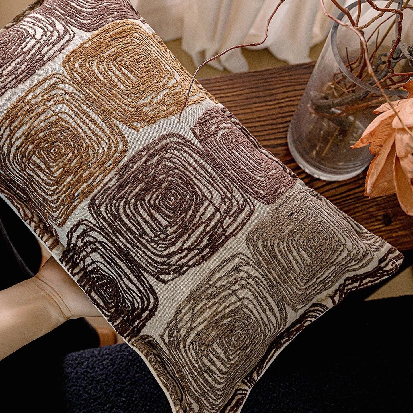 Square and rectangular pillow covers with cream and coffee abstract coil pattern on a sofa.