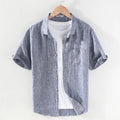 Men's light brown linen shirt with a square collar and short sleeves, shown on a hanger.
