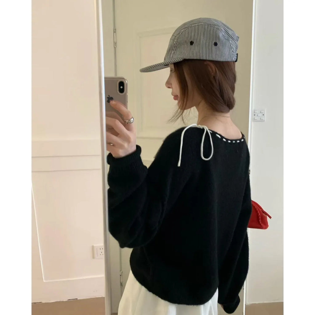 A grey loose-fitting women's knitwear pullover sweater on a hanger.