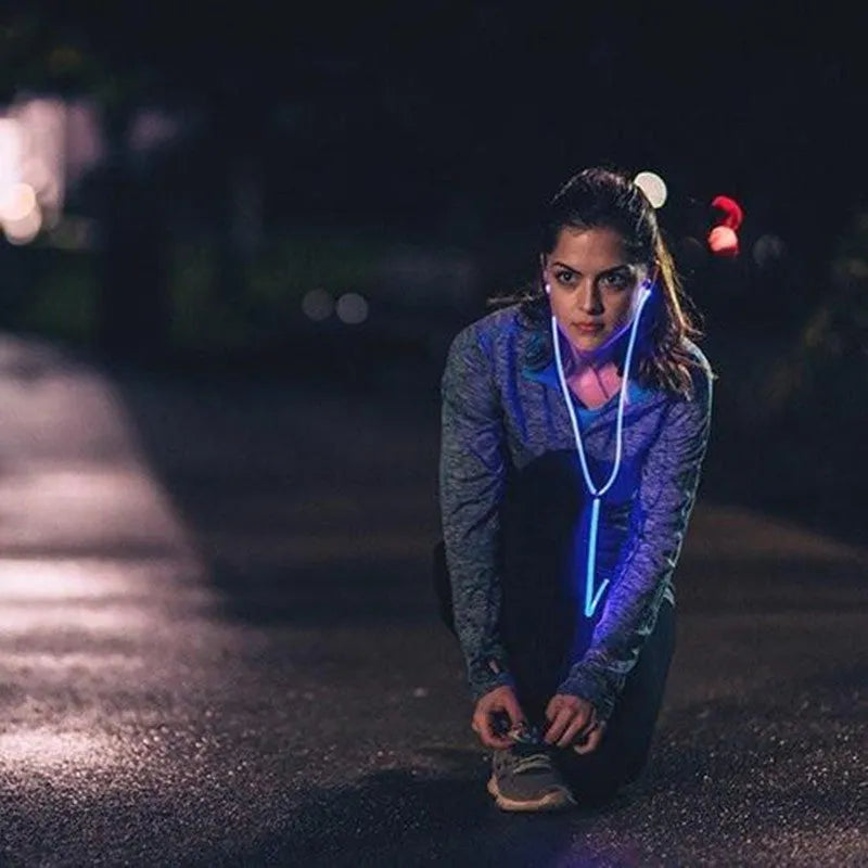 Close-up of blue LED earphones with aluminium alloy shells lit up, showing 3.5mm plug and inline remote.