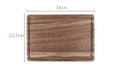Black walnut wood chopping board with juice groove, shown in round and rectangular sizes on a kitchen counter.