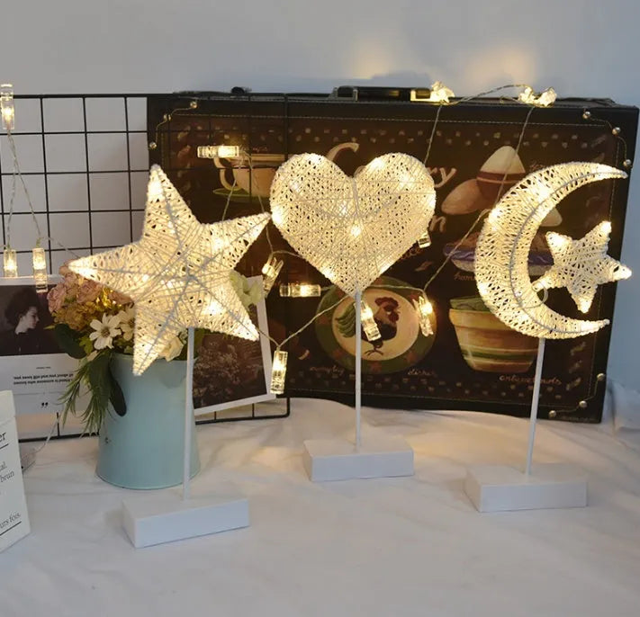 Rattan and copper wire LED table lamp in a star shape on a bedside table.