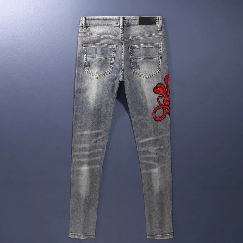 Men's vintage washed slim fit jeans with distressed holes and embroidered patch detail in old colour.