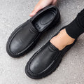 Men's black slip-on work shoes with a mid-top waterproof platform sole on a white background.