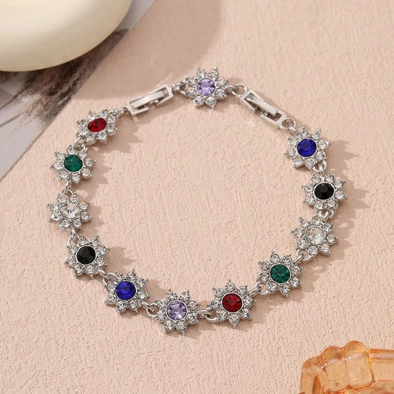 Gold tone flower-shaped bracelet with blue crystal gems on a wrist.