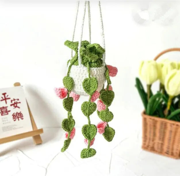 Green and white knitted car plant decoration with hanging rope on car dashboard
