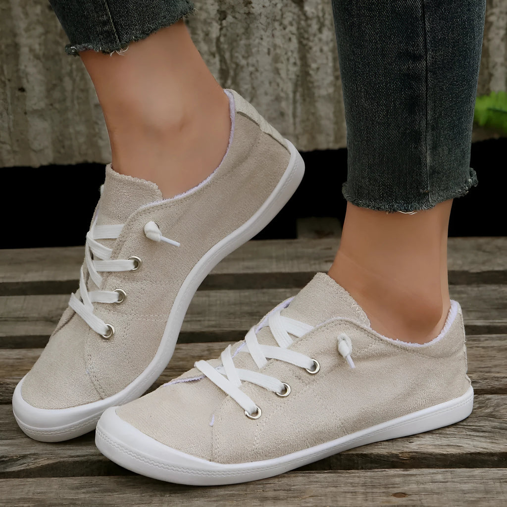 Women's low-top creamy white fabric sneakers with a wear-resistant rubber sole on a neutral background.