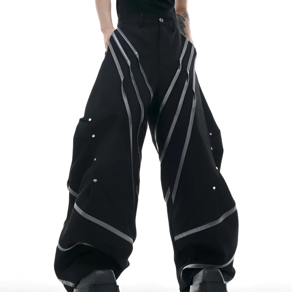 Men's black polyester trousers with metal striped rivet decoration and pleats, showing three-dimensional cut.
