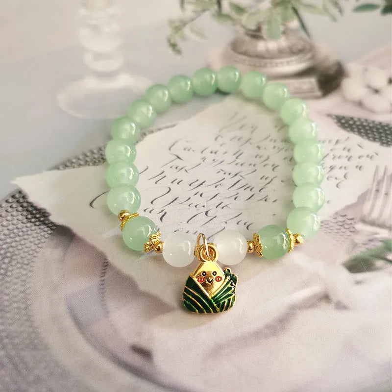 A Chinese style glass bracelet with bamboo leaf and bead designs on a wrist.