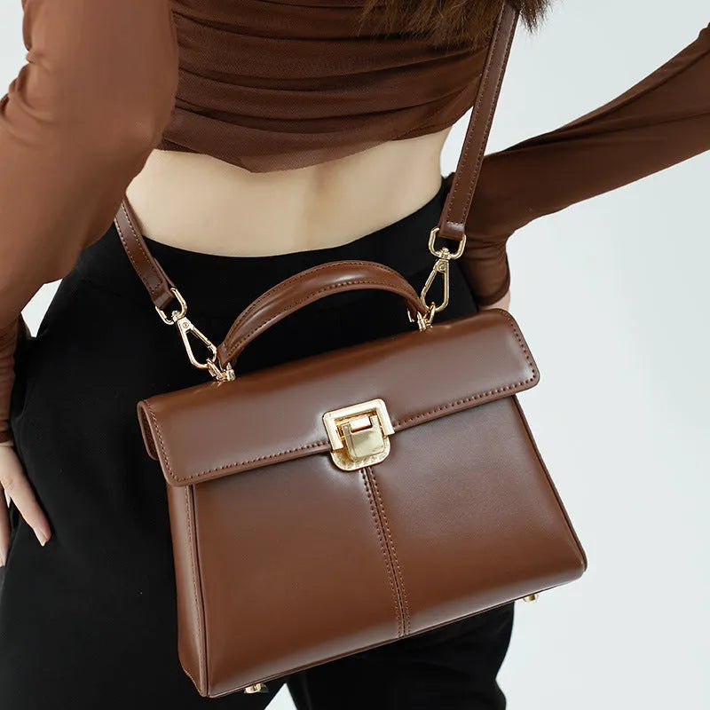 Black genuine leather shoulder bag with clasp closure showing internal compartments and adjustable strap