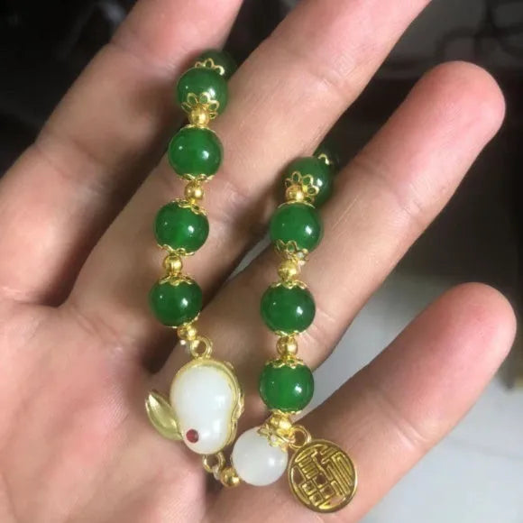 A Chinese style glass bracelet with bamboo leaf and bead designs on a wrist.