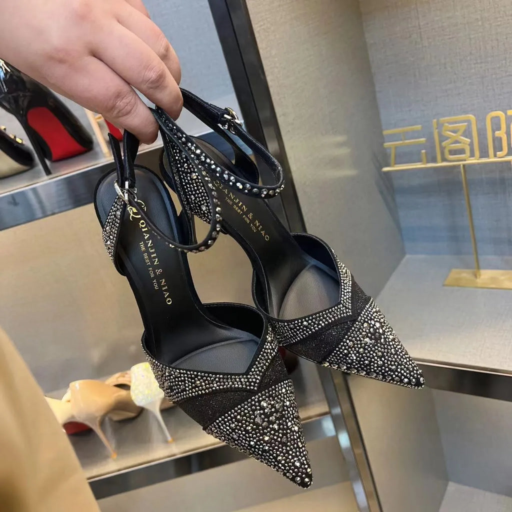 Women's black high heel shoe with stiletto heel, pointed toe, shallow cut, and red sole.