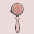 Green and pink dual-sided pet grooming brush with silicone massager and retractable slicker brush.