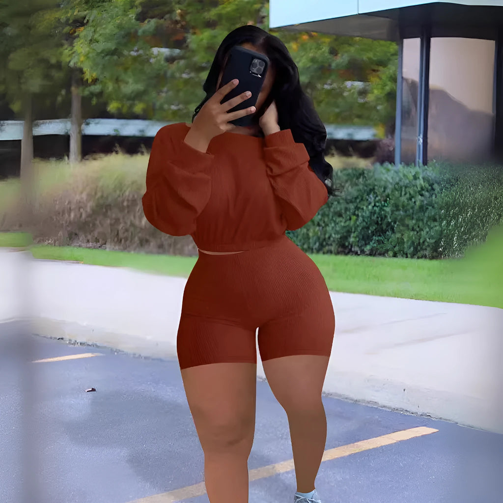 A woman wearing a solid colour off-the-shoulder long-sleeved top and matching shorts from a two-piece set.