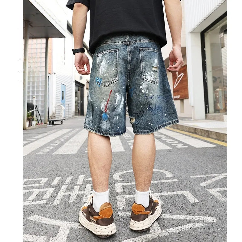 Blue mens denim shorts with ripped knees and graffiti design, straight leg fit.
