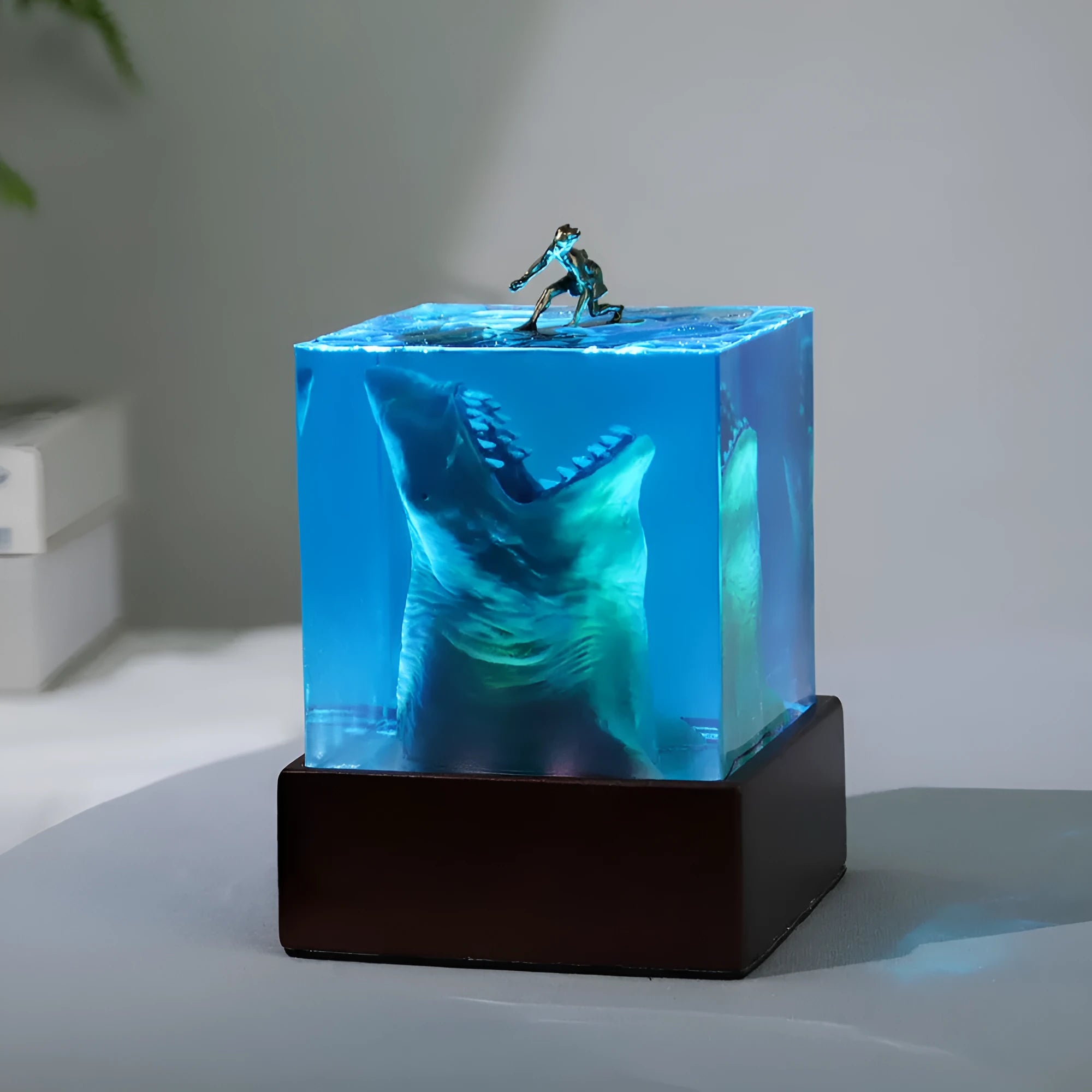 Clear epoxy resin ornament with a shark surfing scene inside, shown next to a 5cm and 8cm size option.