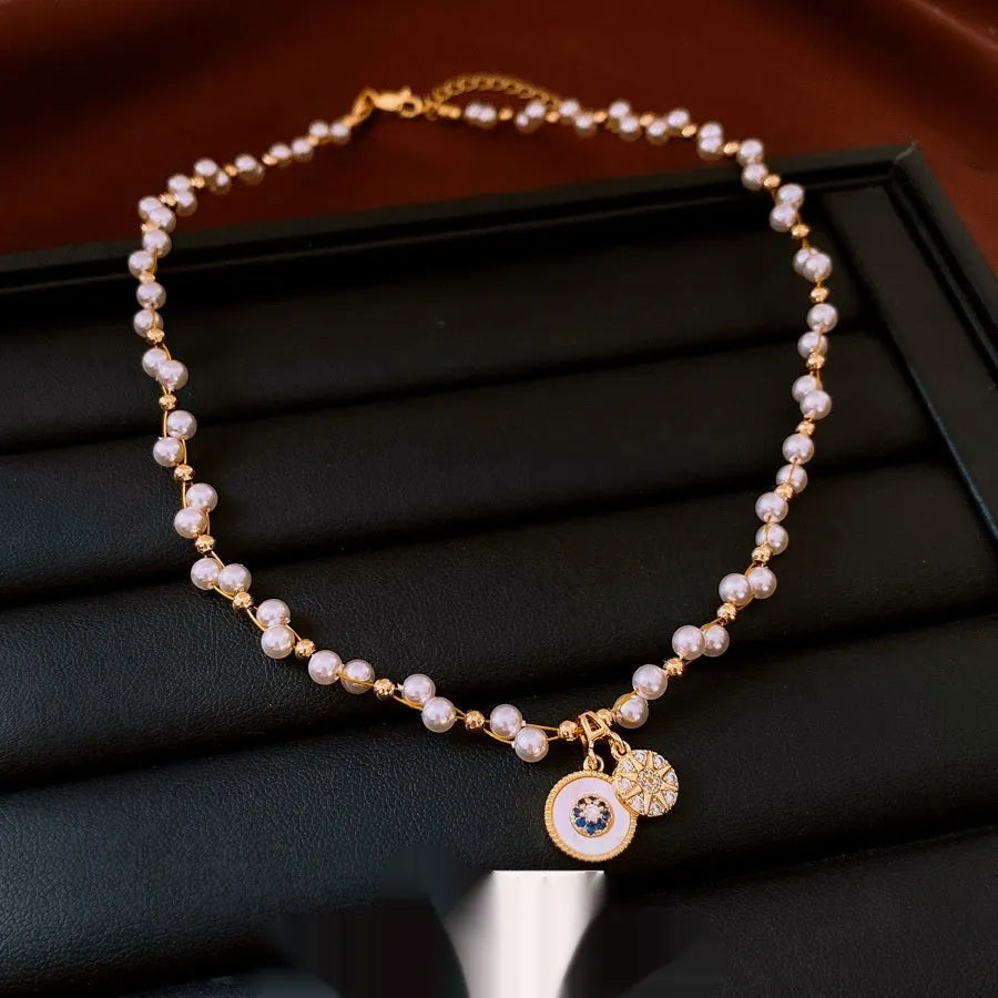 Gold electroplated zircon and imitation pearl round pendant on an adjustable clavicle chain necklace.