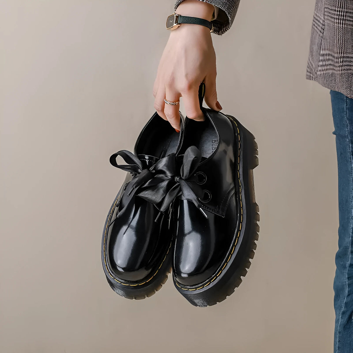 Women's black leather shoes with thick soles, cross straps featuring ribbon details, and lace-up closure
