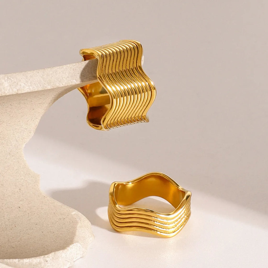 Stainless steel wide band ring with a geometric wave design in a Korean style.