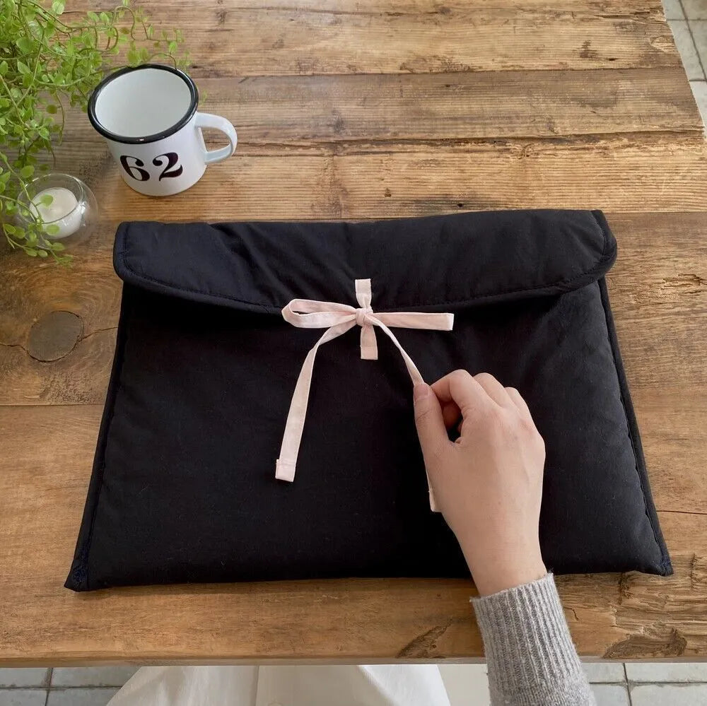 Black and white quilted women's laptop bag with striped pattern and ballet bow detail.
