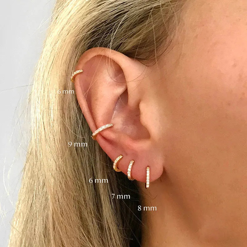 A pair of small circular zircon stud earrings with a metallic finish, shown next to a ruler indicating available sizes from 5mm to 12mm.