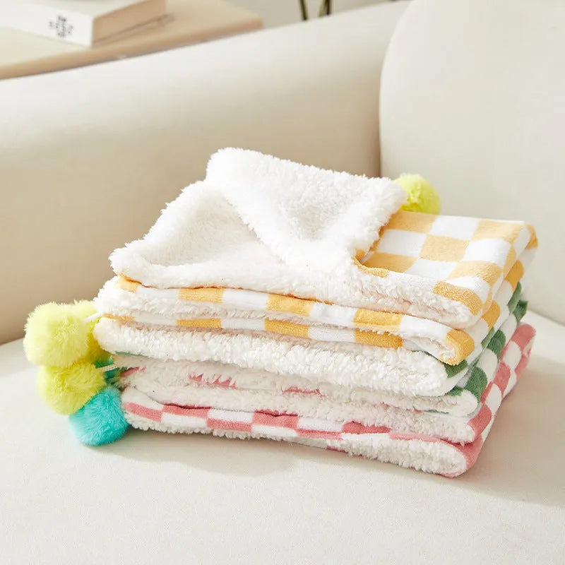 Green plaid pattern pet blanket with fur ball decoration on sofa