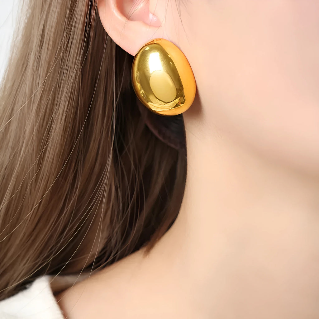 A pair of geometric stainless steel ear studs with a linear design and a glazed gold-coloured surface.