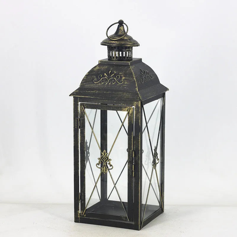 Black wrought iron floor lantern with tempered glass panels, standing on a patio.