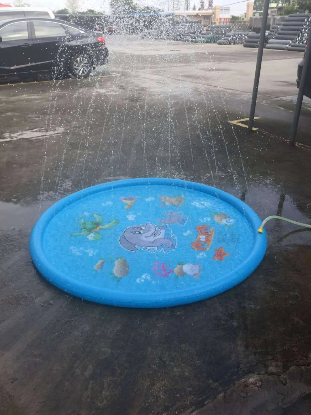 Blue PVC children's water spray mat with marine animal graphics, laid flat on grass.