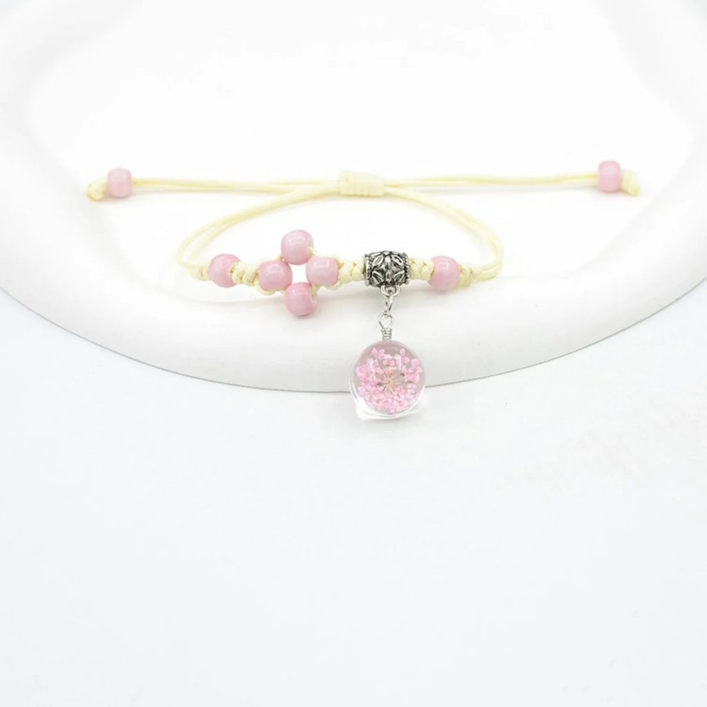 Close-up of a hand-woven glass bracelet with large beads containing dried flowers in multiple colour options.