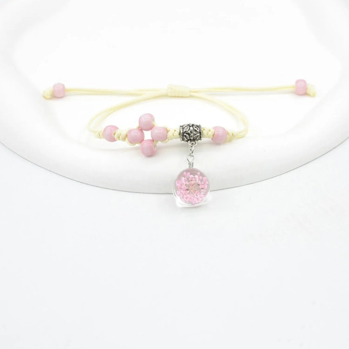 Close-up of a hand-woven glass bracelet with large beads containing dried flowers in multiple colour options.